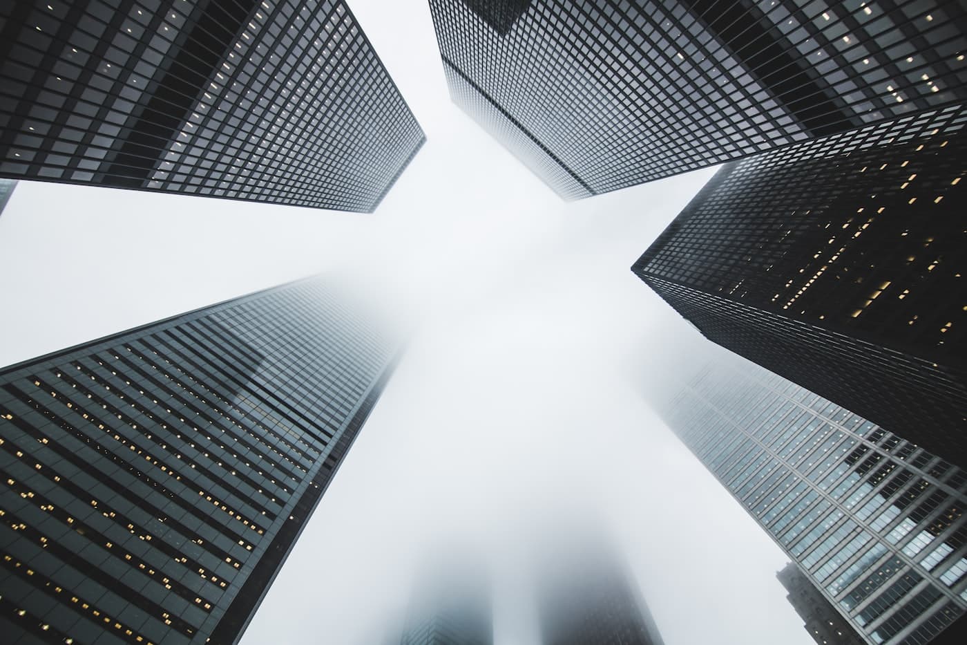 Glass commercial towers converging against a bright sky