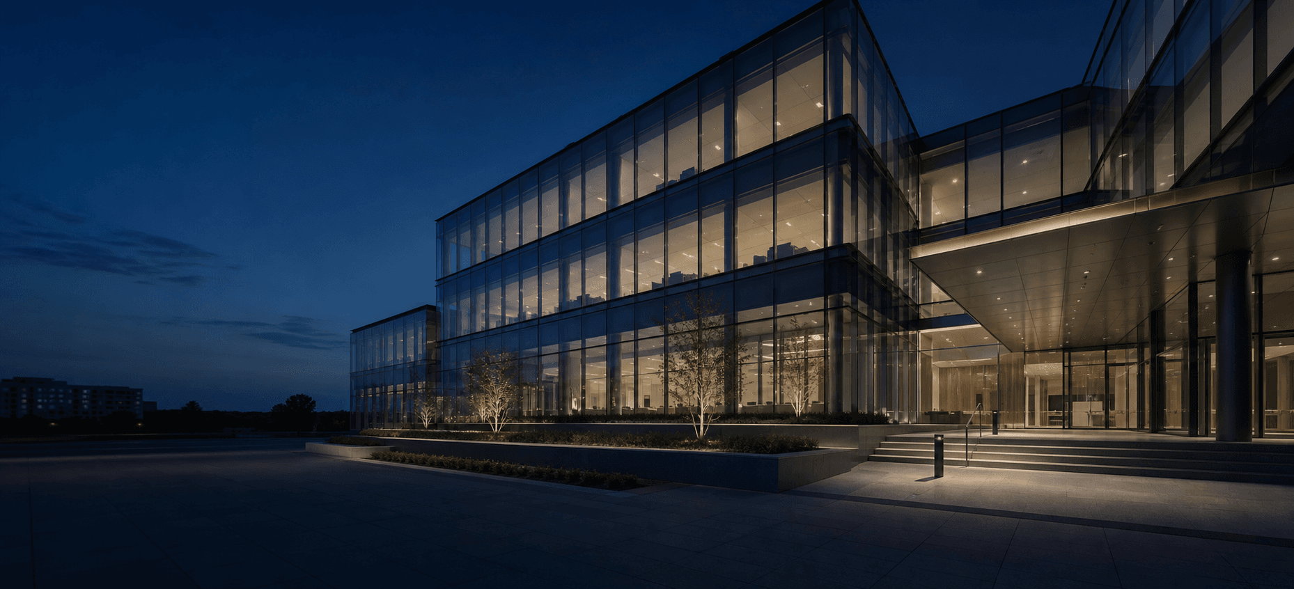 Modern glass corporate headquarters illuminated at blue hour